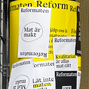 En gul plansch med texten Reformaten och andra vita påklistrade lappar med texten Mat är makt.