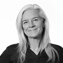 Svartvit porträttbild på AMi Hovstadius som ler med stängd mun.