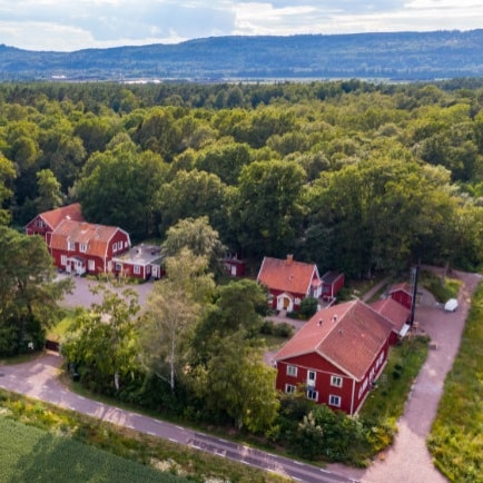 Foto taget högt uppifrån på de röda husen som står intill en stor skog.