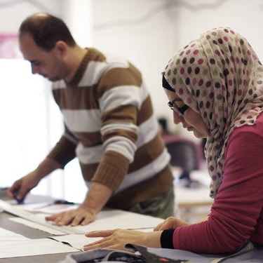 Forum Skill där två personer hänger över ett bord och arbetar koncentrerat.