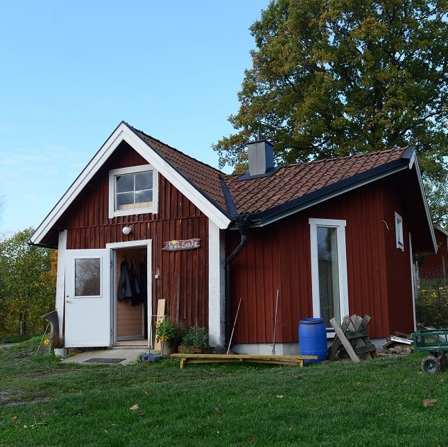 Ett rött hus med vita knutar och grönt gräs gramför.