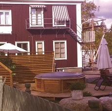 Altanen utanför det röda huset har en rund pool uppepå.